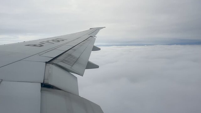 View from an airplane window showing the wing above a vast layer of white clouds. Bright sky stretches across the horizon during flight over Russia.