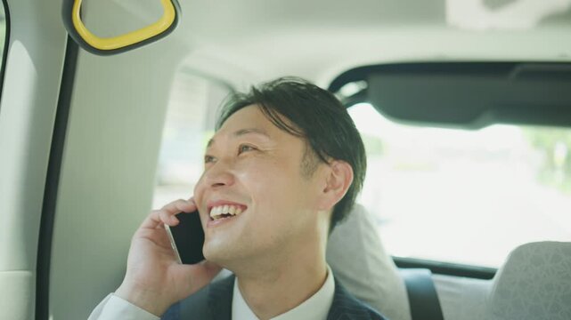 Japanese businessman smiling on a phone call during a taxi ride