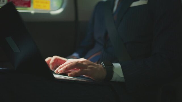 Businessman typing on a laptop in the dim interior of a taxi