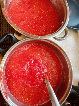 Tomato juice prepared for further cooking. Homemade tomato juice prepared in a cooking pot before further heating and preservation. The rich red liquid made from ripe tomatoes illustrates seasonal foo