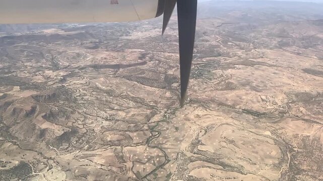 Aerial view from a propeller plane flying over a dry, mountainous terrain in Ethiopia