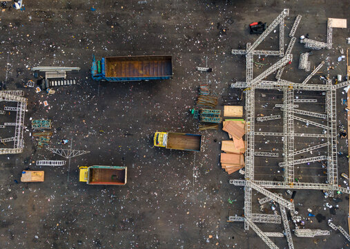 Aerial view of an event site with parked trucks, metal scaffolding structures, and scattered debris on an asphalt surface Purwokerto, Central Java, Indonesia.