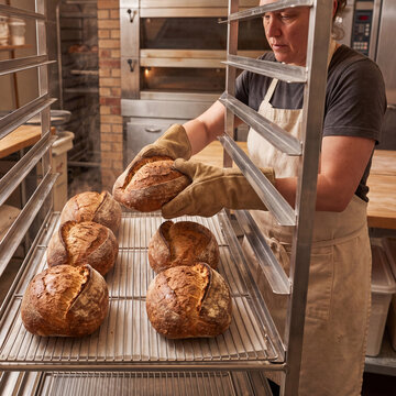 Baker arranging bread loaves on commercial cooling rack