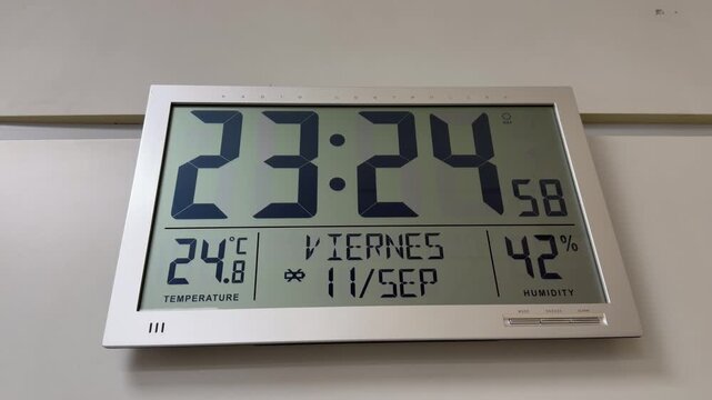 Digital wall clock displaying real time hour temperature date and humidity level indicators on a facility wall