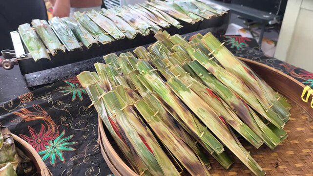 Traditional otak-otak is being cooked on a grill. It is carefully prepared and served hot for eager customers.