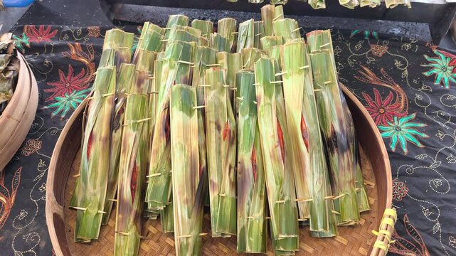 Traditional otak-otak is being cooked on a grill. It is carefully prepared and served hot for eager customers.
