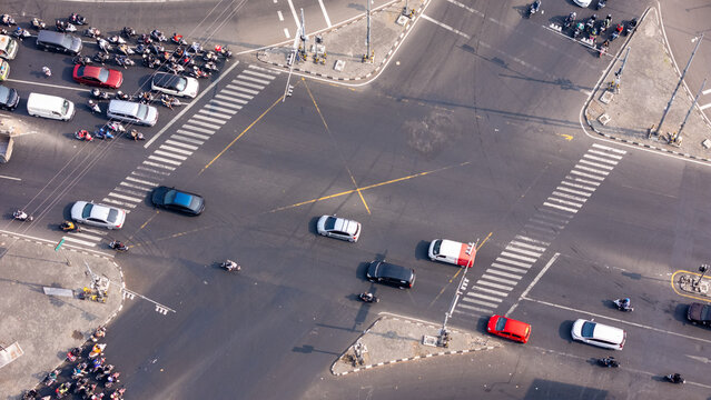 Aerial view of a busy intersection in Yogyakarta with cars and motorcycles, featuring crosswalks and urban traffic flow in Yogyakarta, Special Region of Yogyakarta, Indonesia.