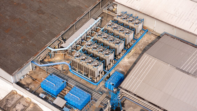 Aerial view of industrial HVAC cooling towers and blue water tanks on a factory rooftop in Yogyakarta, Special Region of Yog, Indonesia.