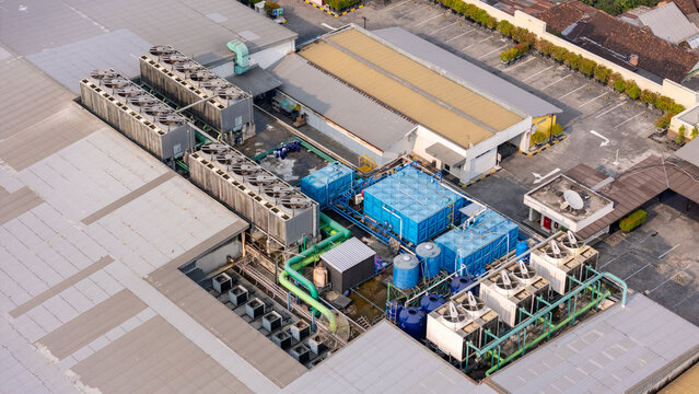 Aerial view of industrial rooftop cooling towers and water storage tanks on a large commercial building in Yogyakarta, Special Region of Yogyakarta, Indonesia.