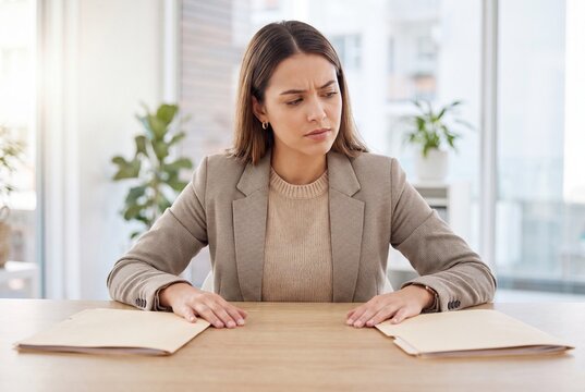 Young professional woman comparing two documents on a desk in a bright modern office setting