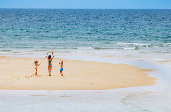 Mom with kids jump and danse on a sandy small island in ocean