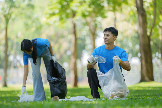 Asian volunteers collecting plastic trash in park for environmental cleanup