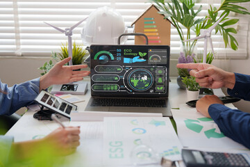 Hands pointing at laptop screen showing ESG energy consultation dashboard during green business...