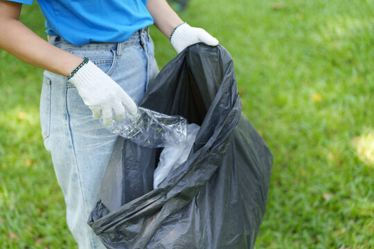 Volunteer picking up plastic trash in park for environmental cleanup