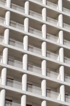 Repeating white balconies and columns form a minimalist residential facade showing clean geometry and an elegant urban architectural detail