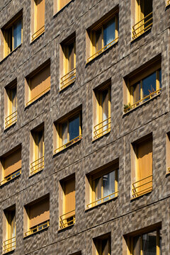 Warm light on apartment facade with repeating windows creates an urban architectural detail showing residential texture geometry and city design