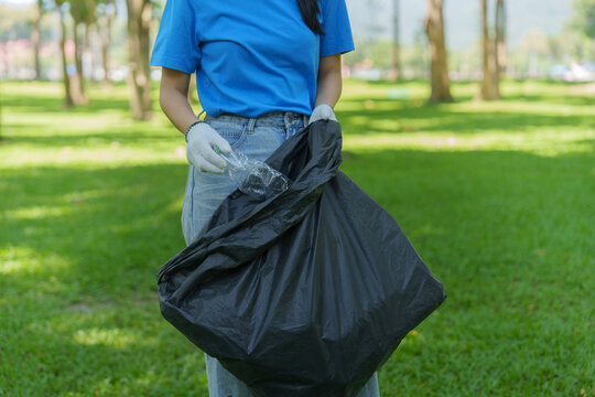 Volunteer collecting plastic bottle in park for community garbage cleanup