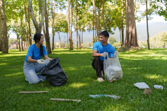 Asian volunteers collecting trash in park for environmental cleanup