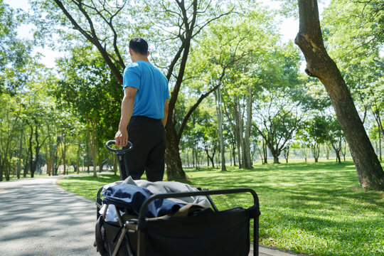 Volunteer man pulling wagon of donated clothes in park for community service