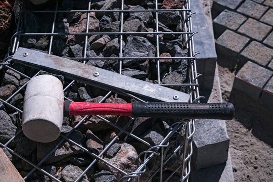 Rubber mallet and construction tool lying on gabion mesh wall outdoors
