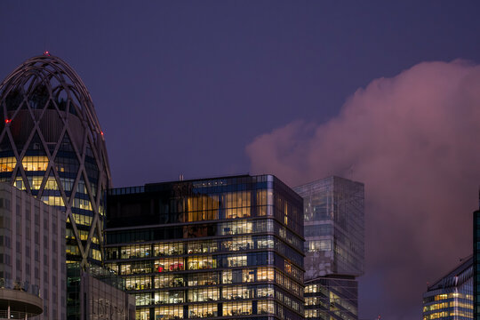 Modern office buildings in La Defense Paris France glow at dusk beneath dramatic clouds creating a contemporary business district cityscape