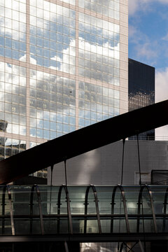 Reflective glass towers in La Defense Paris France rise above a pedestrian bridge showing modern business architecture and layered urban design