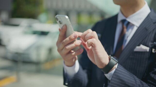 Close up of a businessman's hands operating a smartphone outdoors