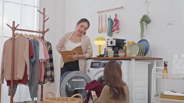 Laundry room woman washing machine clothing rack home interior domestic life towel kitchenware shelf reading with women folding clothes beside washer and drying rack bright home interior laundry room