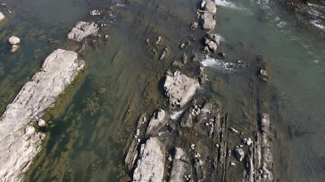 Aerial Scenery of Rugged Rock Formations with Vegetation Sprouting on and Around the Rocks in a Clear Turquoise River During Morning in Wangon, Central Java, Indonesia. 