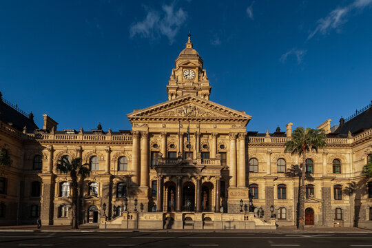 View of the historic Cape Town City Hall with its prominent clock tower and stone facade under a clear blue sky in Cape Town, Western Cape, South Africa.