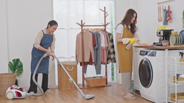 Laundry room cleaning with woman vacuum cleaner and washing machine in bright home interior, clothes on rack, domestic chore task
