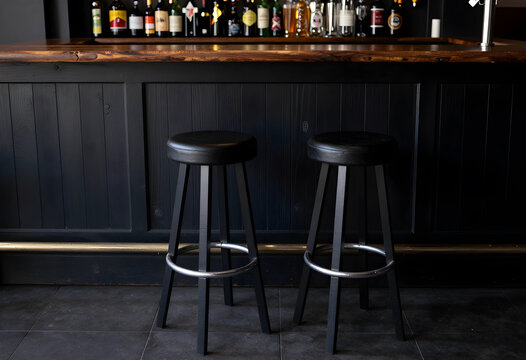 Hospitality and nightlife industry, empty bar stools at a dark wooden counter in a pub or restaurant for social gathering and leisure time atmosphere