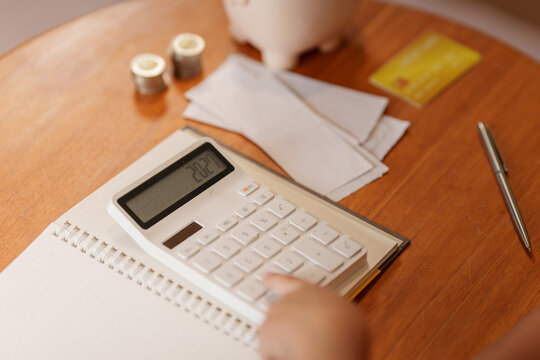 Hand using calculator for financial budgeting and tax planning on wooden desk