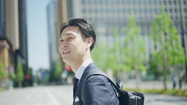 Smiling businessman walking through the office district with a backpack