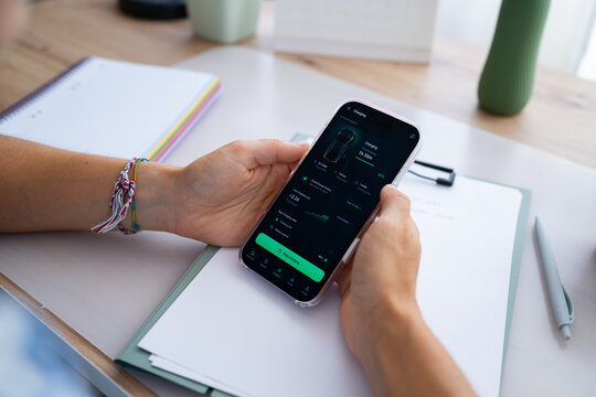 Electric car charging app on smartphone held over desk with notebook
