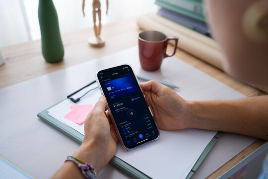 White person using digital wallet app on mobile phone at desk in Spain