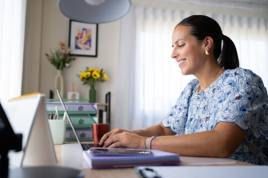 White woman working on laptop in a bright home office in a office