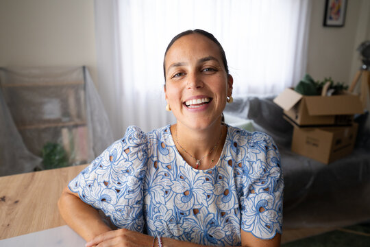 Smiling white woman at table in home office with moving boxes