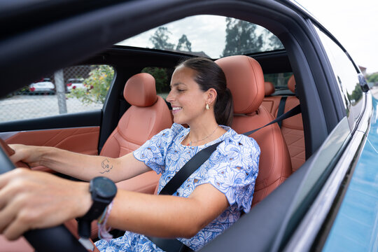 White woman driving modern car with leather interior and open sunroof