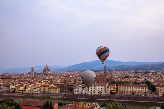 View of hot air balloons floating over the historic skyline of Florence with the Cathedral of Santa Maria del Fiore and the Arno river in Florence, Tuscany, Italy.
