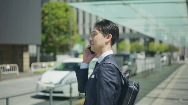 Japanese businessman on a phone call beside a waiting taxi