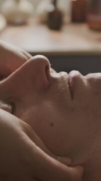 Vertical video of Caucasian adult receiving rejuvenating facial massage by professional therapist in spa salon. Ideal for beauty marketing and wellness advertising