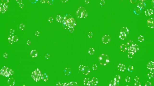 Iridescent Bubbles Green Screen. A large number of soap bubbles moving in one direction against a green background. Great for use in blending