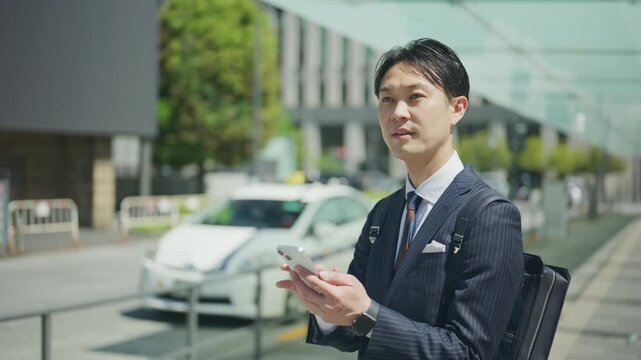 Businessman operating his smartphone next to a taxi stand