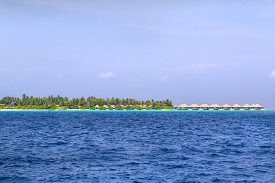 Maldives, Water bungalows and tropical island resort view across the ocean.