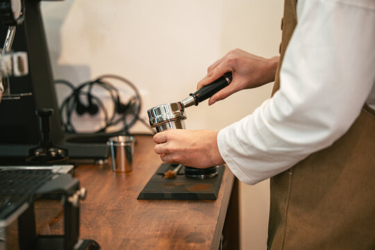Cafe Barista Preparing a Portafilter at a Coffee Counter, Showing a Caucasian Woman Handling Espresso Equipment During Drink Preparation in a Modern Small Business Cafe Workspace