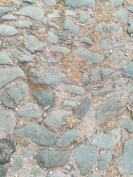 Top-down view of a rustic, uneven cobblestone path made of flat stones and dirt