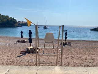 Lifeguard chair stands on an empty sandy beach looking out at the calm blue sea © lmot11