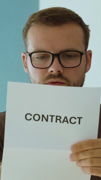 Close-up of a serious man carefully reading a contract document, representing legal agreement, business terms and contract review.