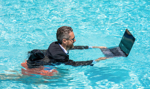 Remote working. Summer business vacation. Funny crazy businessman rest in formal wear in pool. Businessman in suit with laptop in swimming pool. Crazy business man summer vacation. Travel work